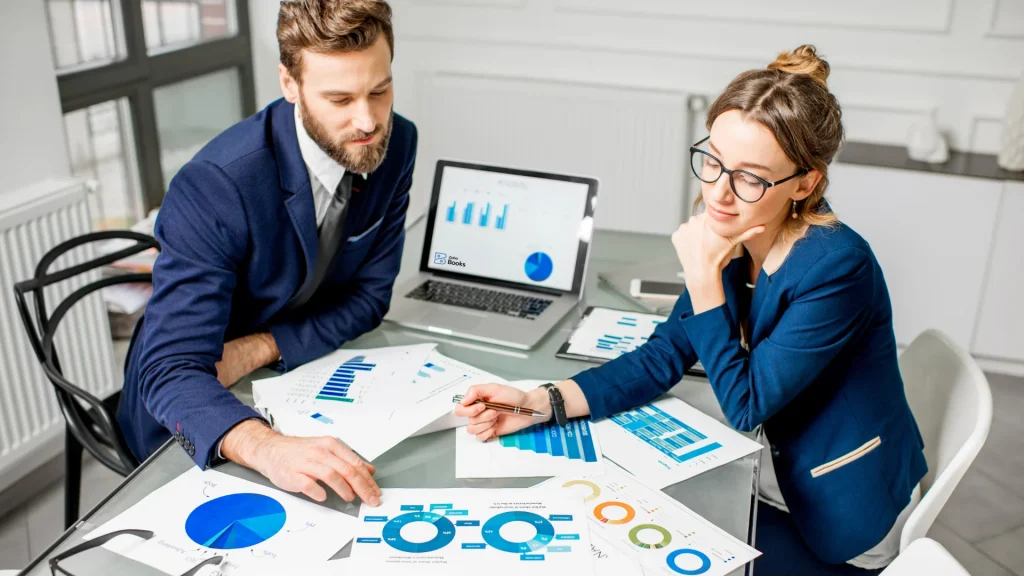 Zoho Books vs. QuickBooks: Which Accounting Software is best for Your Business in 2025? A small team looking relaxed while their screen shows Zoho Books dashboard