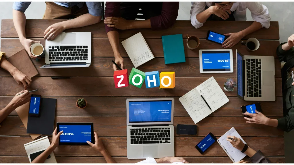 Team collaborating with laptops showing Zoho logo digital workplace concept