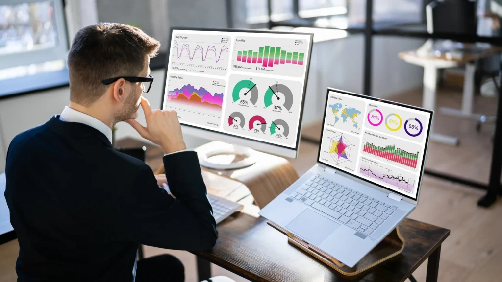 Professional reviewing analytics dashboards on multiple screens illustrating the practical benefits of AWS–Zoho Analytics integration
